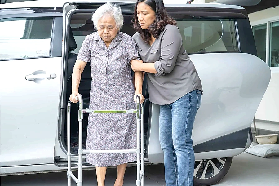 Caregiver supporting an older adult using a walking aid