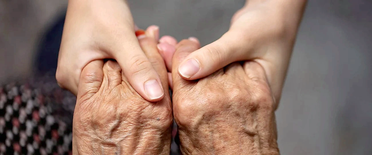 Close-up of caregiver holding an older adult's hand